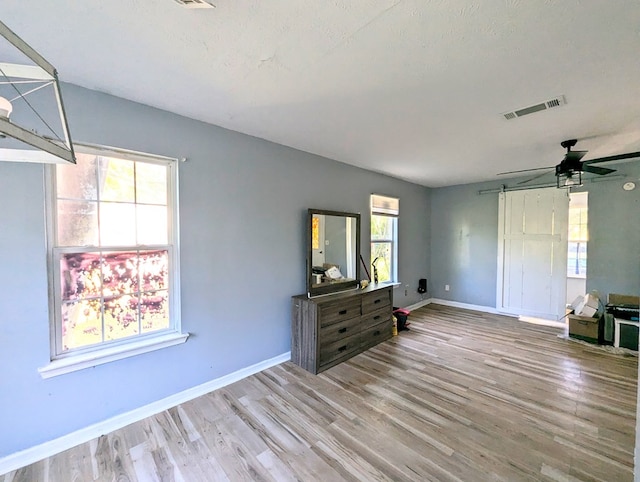 bedroom featuring ceiling fan, light hardwood / wood-style flooring, and multiple windows