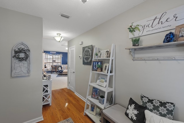 corridor featuring a textured ceiling and hardwood / wood-style floors