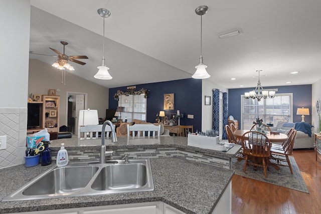 kitchen with hanging light fixtures, dark hardwood / wood-style floors, sink, lofted ceiling, and ceiling fan with notable chandelier