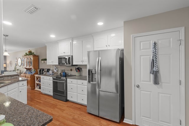 kitchen with decorative light fixtures, stainless steel appliances, tasteful backsplash, light wood-type flooring, and white cabinets