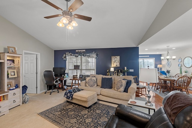 living room with light colored carpet, vaulted ceiling, and ceiling fan with notable chandelier