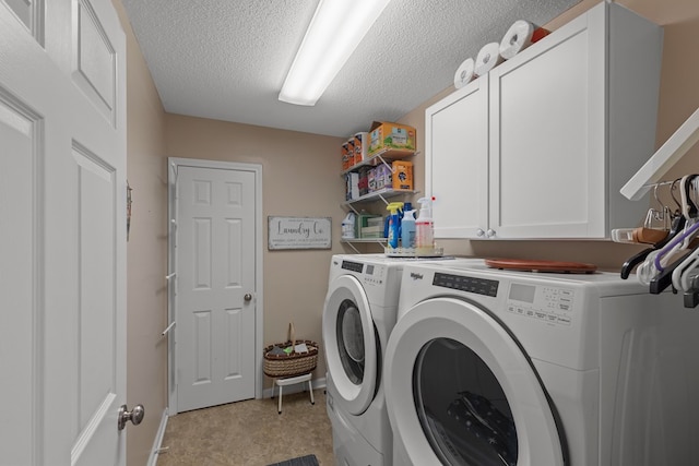 washroom with washing machine and clothes dryer, a textured ceiling, and cabinets