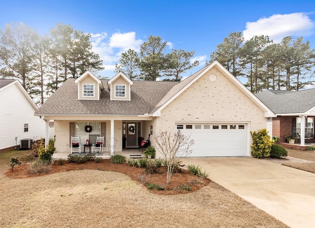 view of front of house featuring covered porch, central air condition unit, and a garage