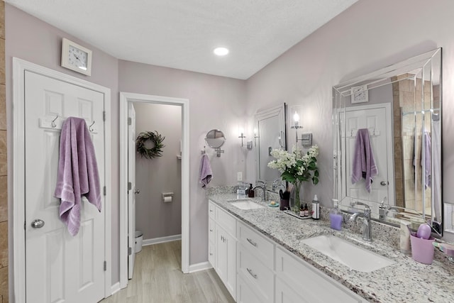 bathroom with a textured ceiling, vanity, and hardwood / wood-style floors