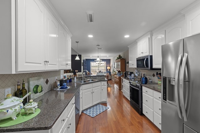 kitchen featuring stainless steel appliances, white cabinetry, sink, and hanging light fixtures