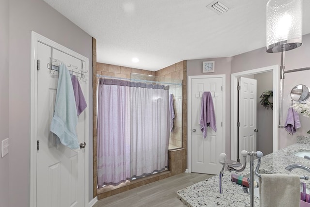 bathroom with a shower with curtain, a textured ceiling, and wood-type flooring