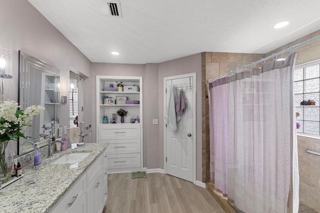 bathroom with curtained shower, a textured ceiling, hardwood / wood-style flooring, vanity, and built in shelves