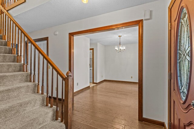 entryway with a textured ceiling, stairs, baseboards, and wood finished floors