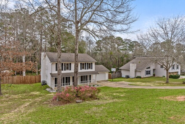 view of front of property featuring a front lawn, a garage, fence, and covered porch