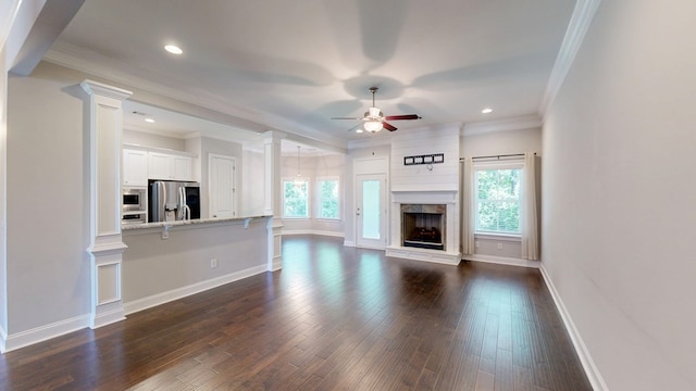 174 Ridgecrest Loop, Dothan, AL 36301 - unfurnished living room featuring a ceiling fan, decorative columns, crown molding, dark wood-style flooring, and baseboards