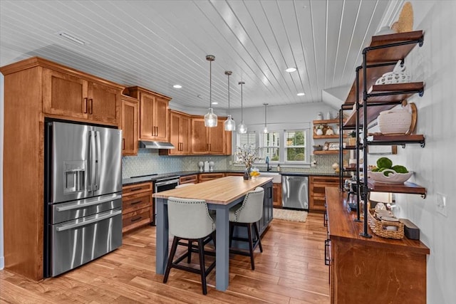 kitchen featuring tasteful backsplash, wooden counters, a center island, hanging light fixtures, and stainless steel appliances