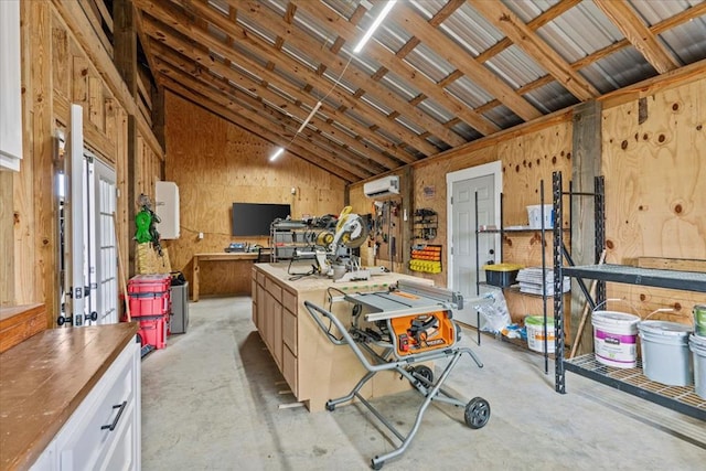 miscellaneous room featuring a wall mounted air conditioner, vaulted ceiling, and a workshop area