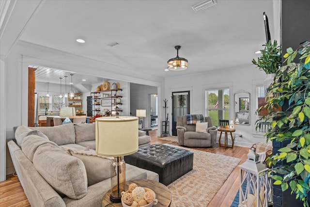 living room featuring ornamental molding, a notable chandelier, and light hardwood / wood-style flooring