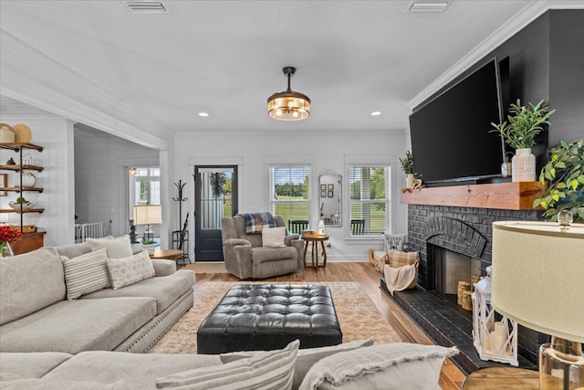 living room featuring a fireplace, crown molding, and wood-type flooring