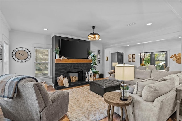 living room featuring crown molding, hardwood / wood-style flooring, a fireplace, and a barn door