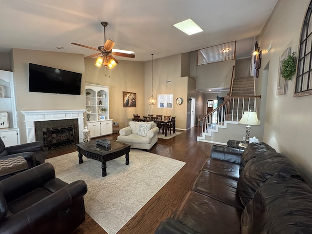 living room with hardwood / wood-style floors, vaulted ceiling, ceiling fan, built in shelves, and a fireplace