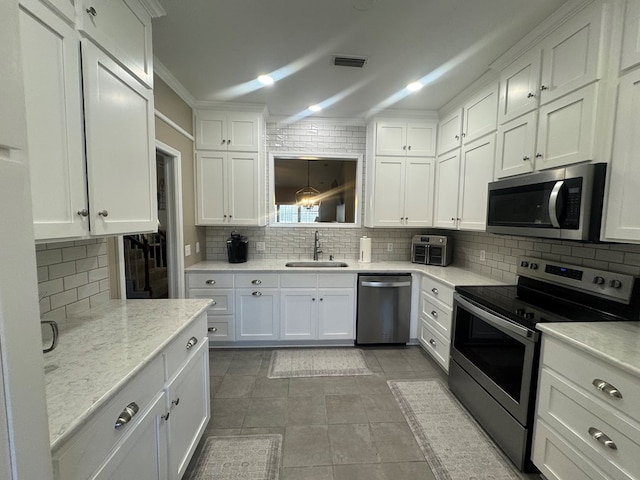 kitchen featuring white cabinetry, sink, stainless steel appliances, tasteful backsplash, and light stone counters