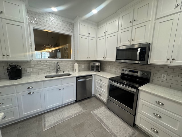 kitchen featuring white cabinetry, sink, tasteful backsplash, light tile patterned floors, and appliances with stainless steel finishes