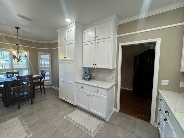 kitchen with decorative backsplash, crown molding, pendant lighting, a notable chandelier, and white cabinetry