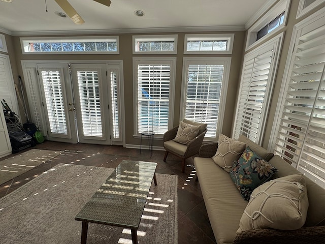 living room with a wealth of natural light, ceiling fan, dark tile patterned flooring, and ornamental molding