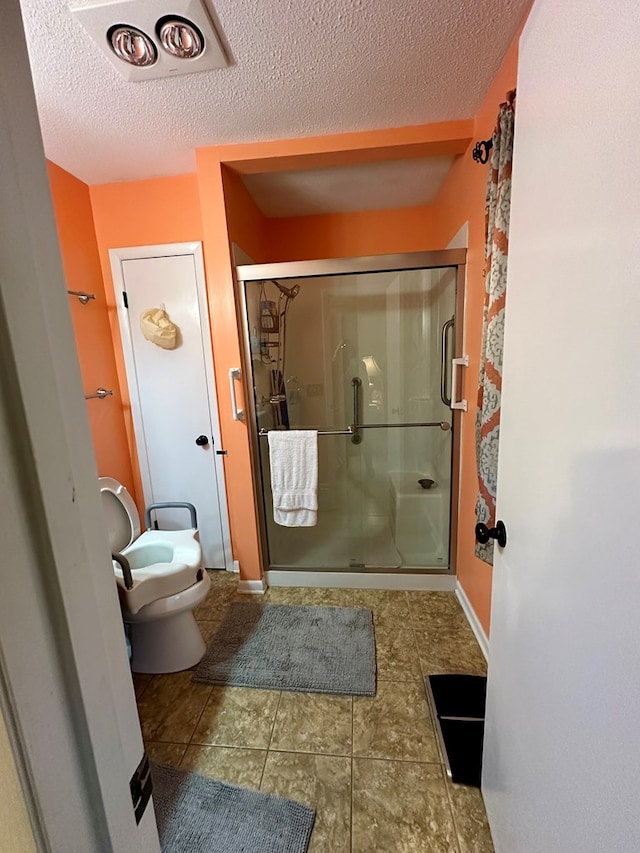 bathroom with a textured ceiling, an enclosed shower, and toilet