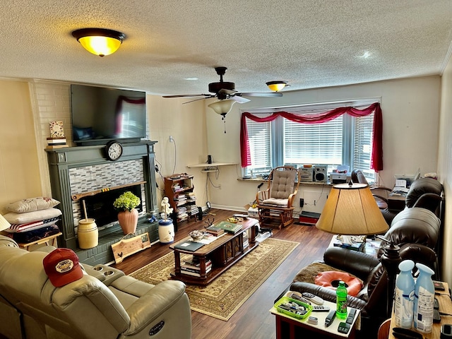 living room with a textured ceiling, a tile fireplace, dark hardwood / wood-style flooring, ornamental molding, and ceiling fan