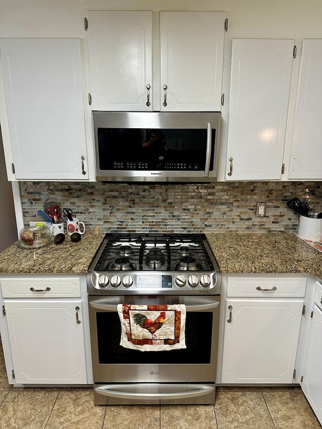 kitchen with appliances with stainless steel finishes, white cabinetry, and dark stone countertops