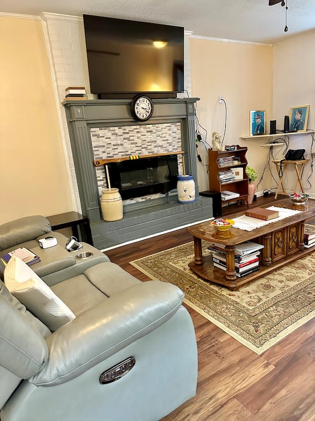 living room with a textured ceiling, ceiling fan, ornamental molding, and wood-type flooring