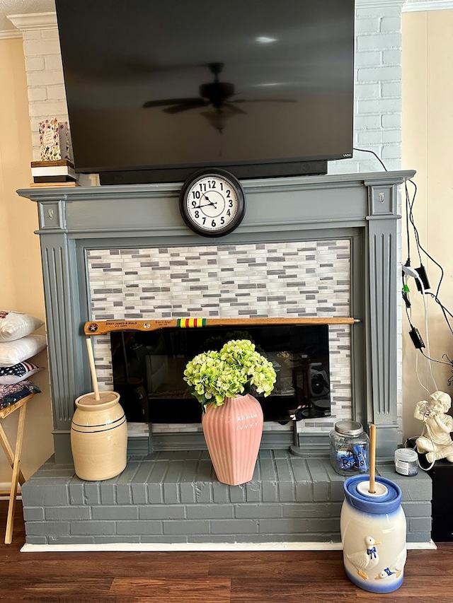 details with ornamental molding, ceiling fan, a brick fireplace, and wood-type flooring