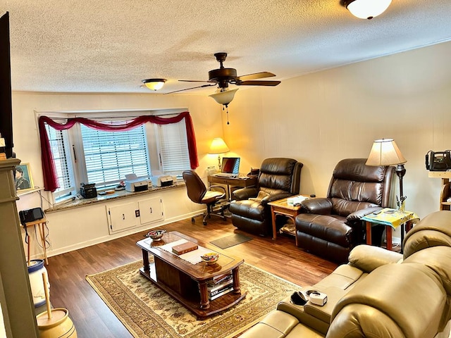 living room with a textured ceiling, dark wood-type flooring, and ceiling fan