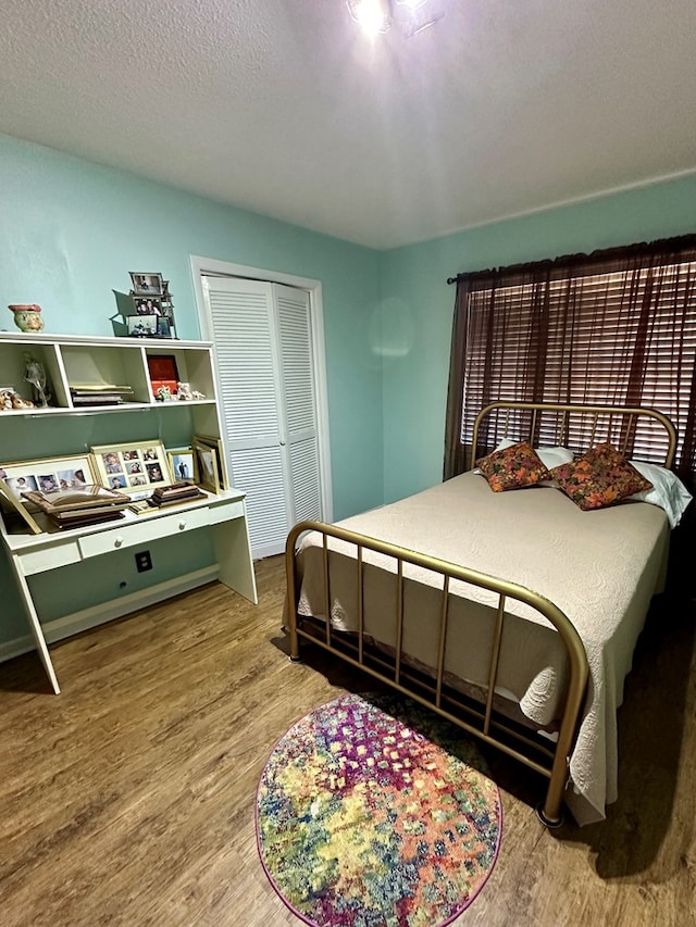 bedroom with a textured ceiling, a closet, and hardwood / wood-style flooring