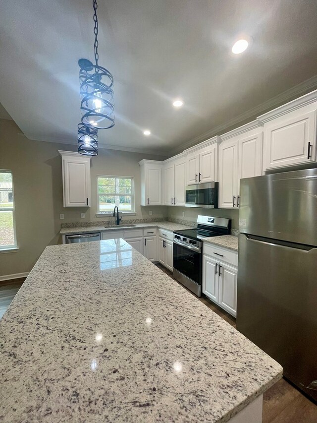 kitchen featuring white cabinetry, hanging light fixtures, stainless steel appliances, and sink