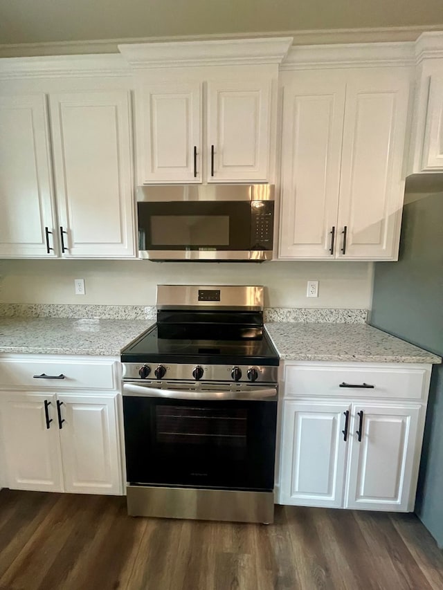 kitchen with appliances with stainless steel finishes, white cabinetry, dark wood-type flooring, and light stone counters