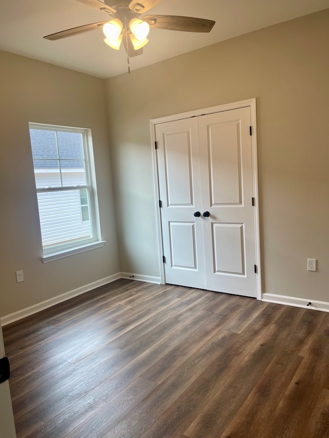 unfurnished bedroom with ceiling fan, a closet, and dark wood-type flooring