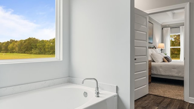 bathroom with a bathtub, ornamental molding, and hardwood / wood-style flooring