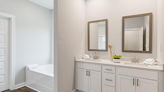 bathroom featuring vanity, wood-type flooring, and a tub to relax in