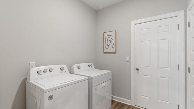 washroom with washing machine and clothes dryer and dark hardwood / wood-style flooring