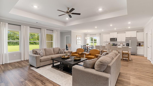 living room featuring light hardwood / wood-style flooring, a raised ceiling, and ceiling fan