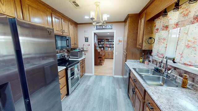 391 Hatton Rd, Dothan, AL 36301 - kitchen with stainless steel appliances, a chandelier, brown cabinetry, light countertops, and ornamental molding