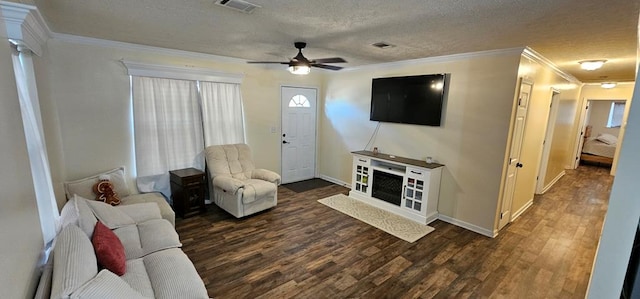 living room featuring dark wood-type flooring, crown molding, a textured ceiling, ceiling fan, and decorative columns