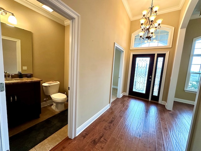 foyer entrance featuring crown molding, sink, hardwood / wood-style floors, and a chandelier