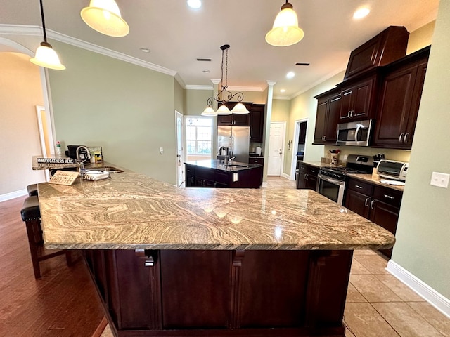 202 Frisco Ln, Enterprise, AL 36330 - kitchen featuring appliances with stainless steel finishes, a center island with sink, baseboards, ornamental molding, and a breakfast bar