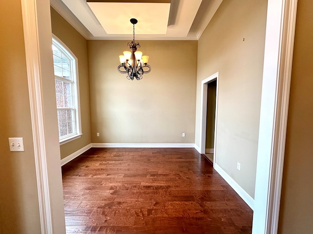 interior space featuring ornamental molding, dark wood-type flooring, a notable chandelier, and a tray ceiling