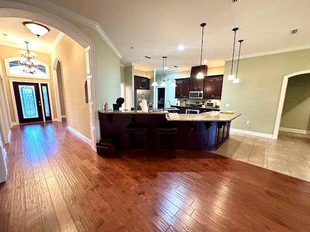 202 Frisco Ln, Enterprise, AL 36330 - kitchen featuring dark brown cabinets, appliances with stainless steel finishes, a breakfast bar area, arched walkways, and ornamental molding