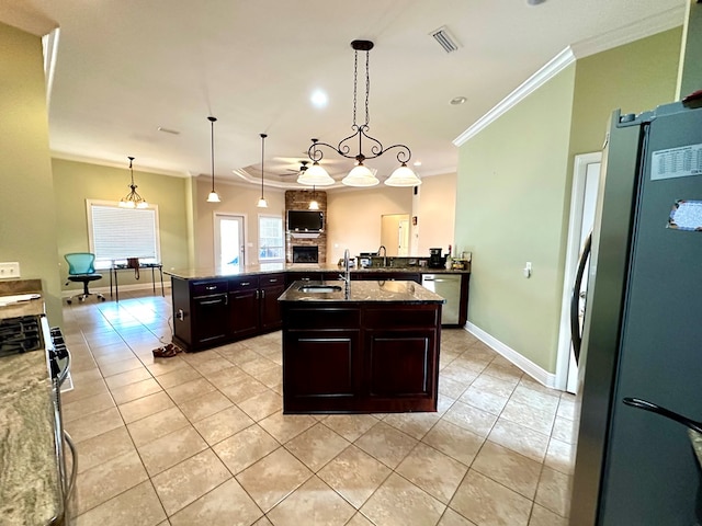 kitchen with an island with sink, sink, hanging light fixtures, stainless steel appliances, and dark brown cabinets