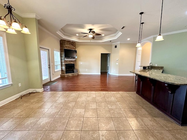 202 Frisco Ln, Enterprise, AL 36330 - kitchen featuring ornamental molding, a stone fireplace, a raised ceiling, light stone counters, and a ceiling fan
