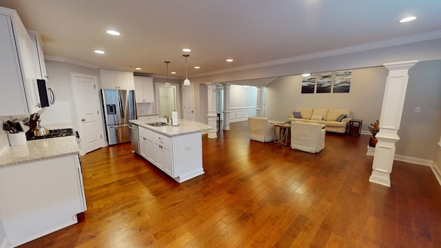 kitchen with white cabinetry, a kitchen island with sink, and hanging light fixtures