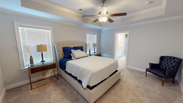 carpeted bedroom with a tray ceiling, ensuite bath, multiple windows, and ceiling fan