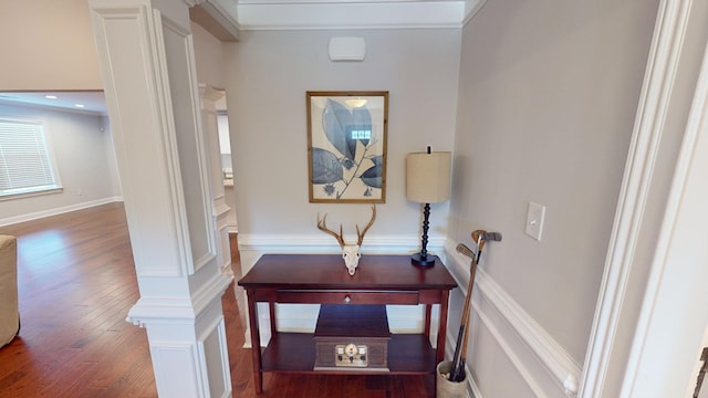 corridor with decorative columns, crown molding, and wood-type flooring