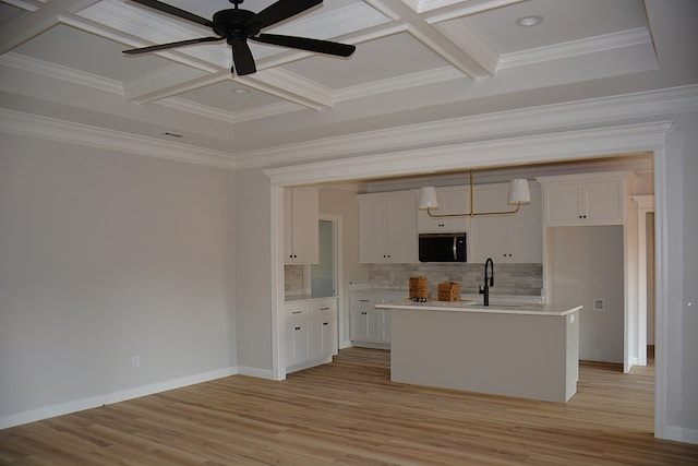 110 Mikala Ct, Enterprise, AL 36330 - kitchen featuring coffered ceiling, stainless steel microwave, white cabinets, a kitchen island with sink, and beam ceiling